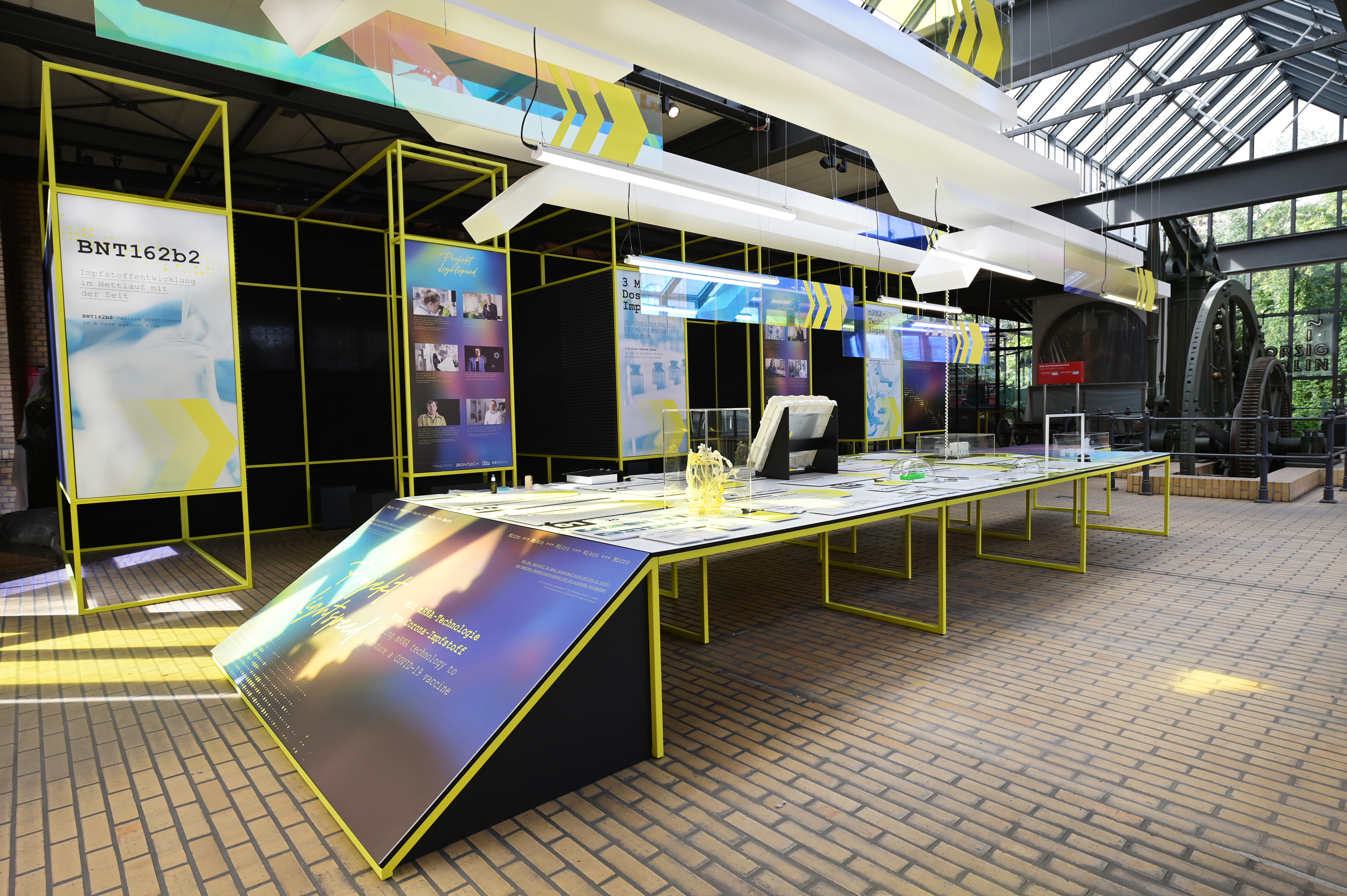 The exhibition table in the locomotive shed, with the booths where film clips are shown behind it.