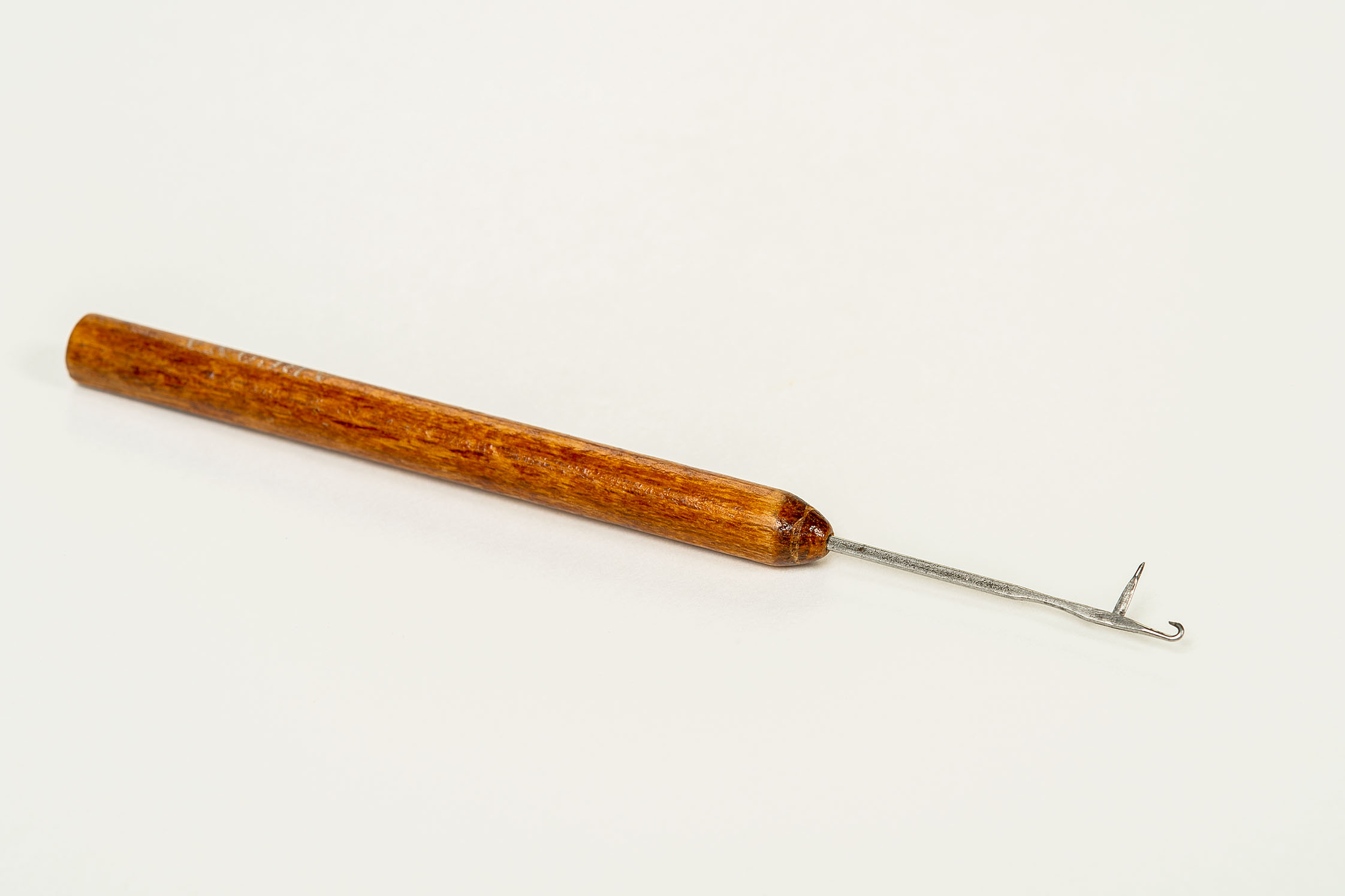 Pictured here is a darning needle: a special needle with a wooden handle used for mending runs in stockings. 