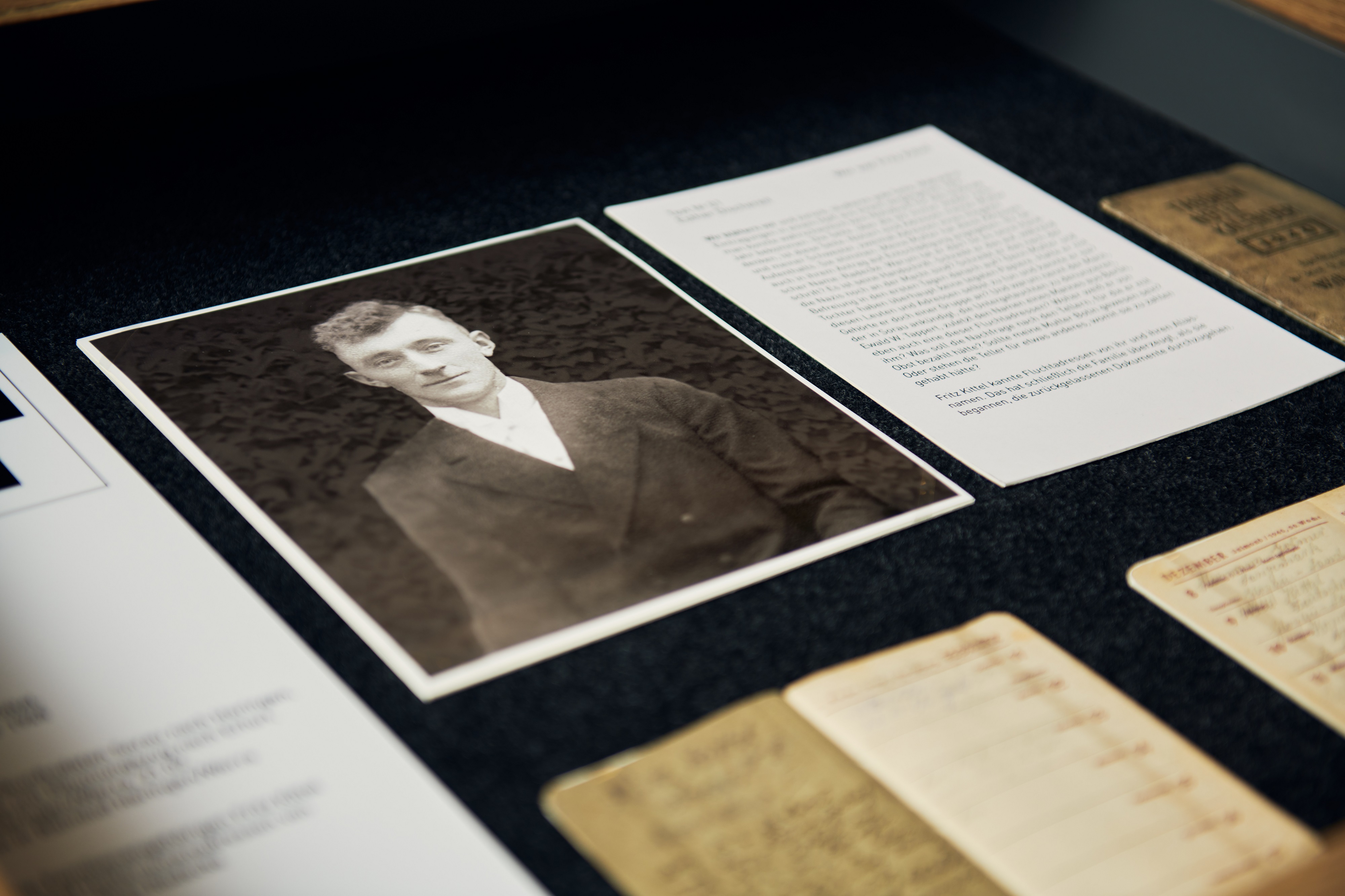 An open drawer. A black-and-white photograph of a young man in a white shirt and dark jacket is visible. Next to it is a typewritten piece of paper. The name "Fritz Kittel" is legible.