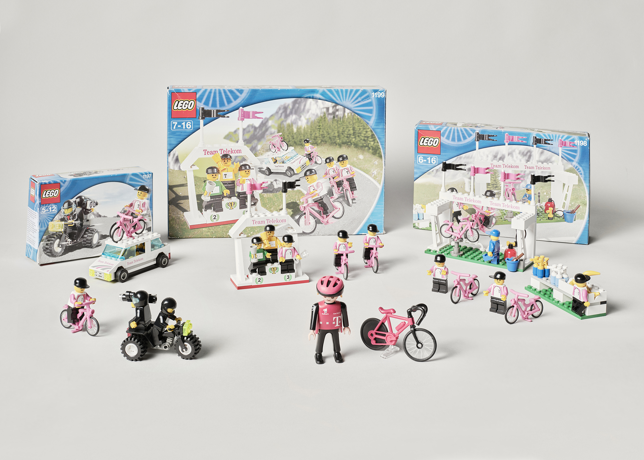 Das Foto zeigt eine Auswahl von Spielzeugen, die Playmobil und Lego zum Team Telekom anboten. Es sind Radfahrer und Rennräder, ein Siegertreppchen, Service- und Kamerafahrzeuge zu sehen.