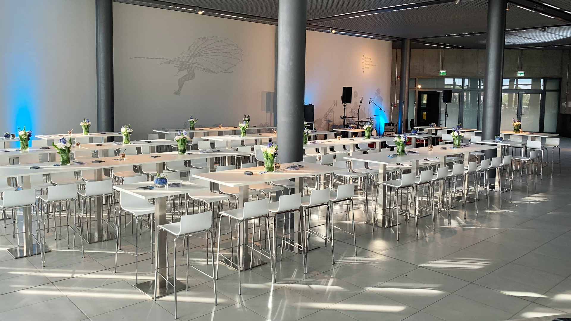 A view of white high chairs and tables in a large room.