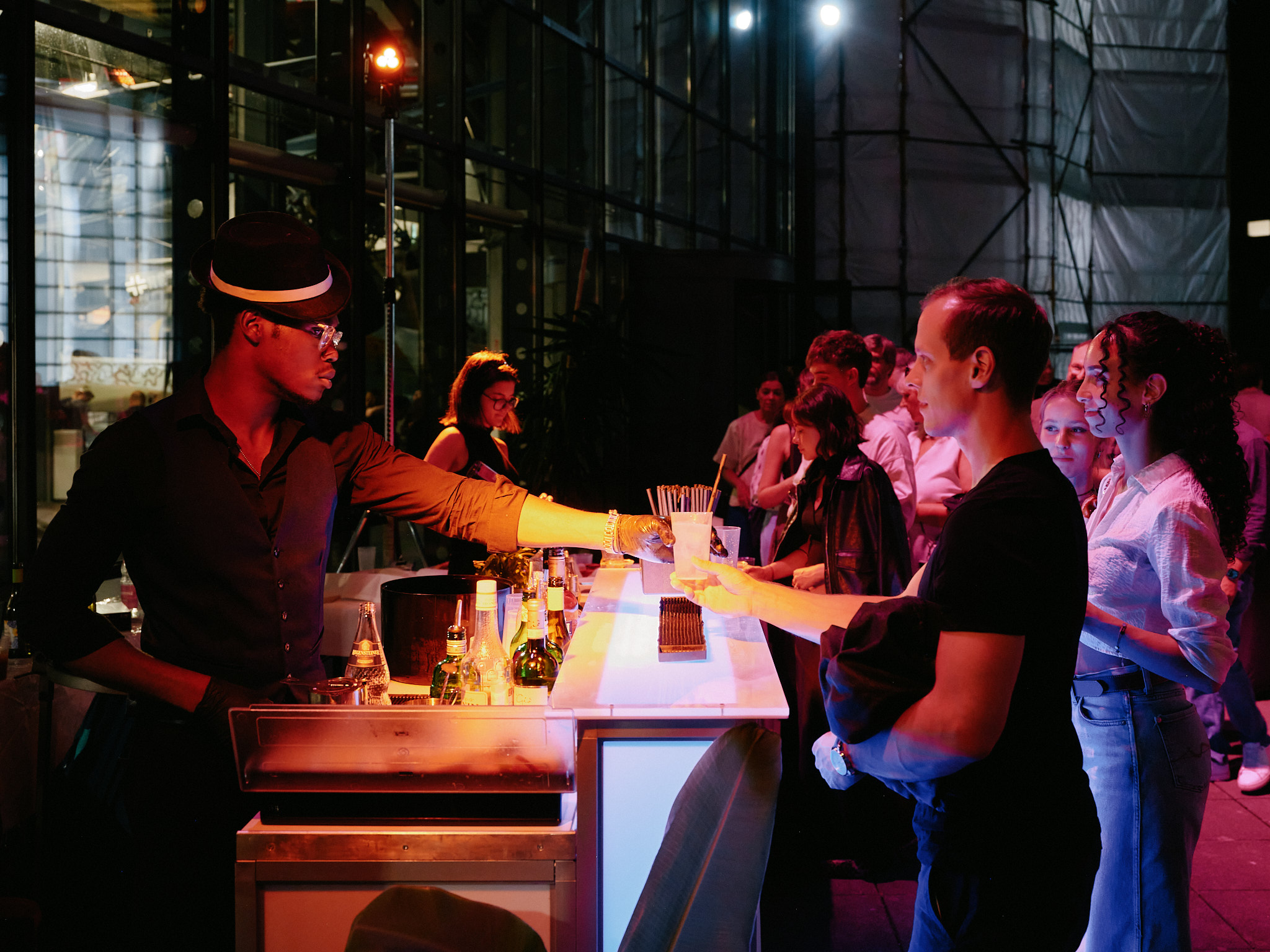 Eine stimmungsvoll beleuchtete Bar auf der Terrasse unterm Rosinenbomber am Deutschen Technikmuseum. Ein Barkeeper bedient Gäste.